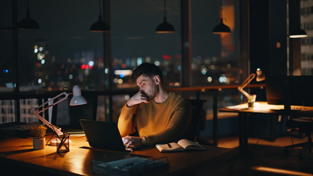 Uomo che lavora al portatile in ufficio di notte