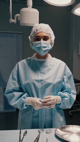 professional surgeon wearing surgical mask, cap, gown, and gloves, stands ready in operating room, surgical instruments arranged on a metal tray in the foreground