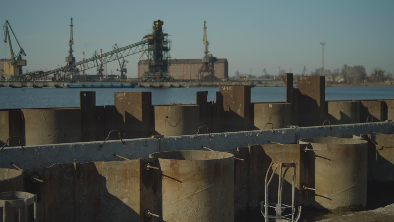 Panning shot of steel reinforcement at construction site with port shore in the background