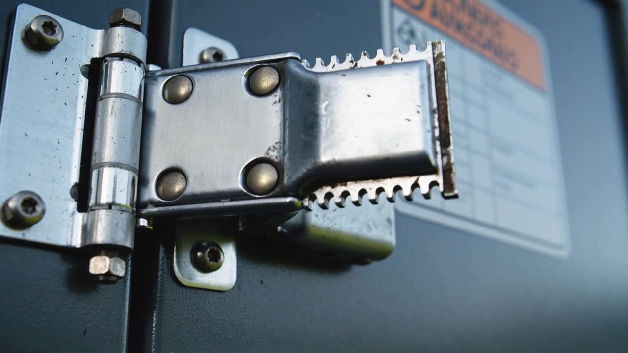 Metal hasp clasp swinging on hinge at metal panel, external pull lifting, revealing serrated teeth