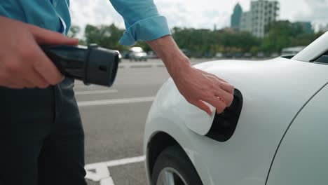 Progressive-businessman-plugs-charger-plug-from-charging-station-to-his-EV.