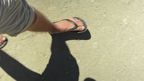 person with beach slippers walking on desert landscape of tenerife, pov