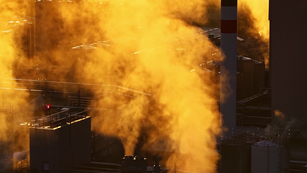 Aerial view of dense smoke from factory chimneys at golden hour, industrial pollution and fumes concept