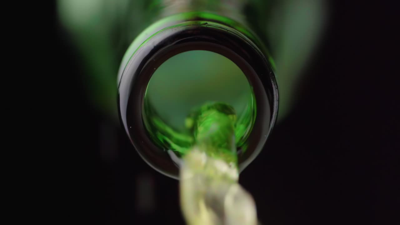 Liquido cristallino versato da una bottiglia di vetro verde