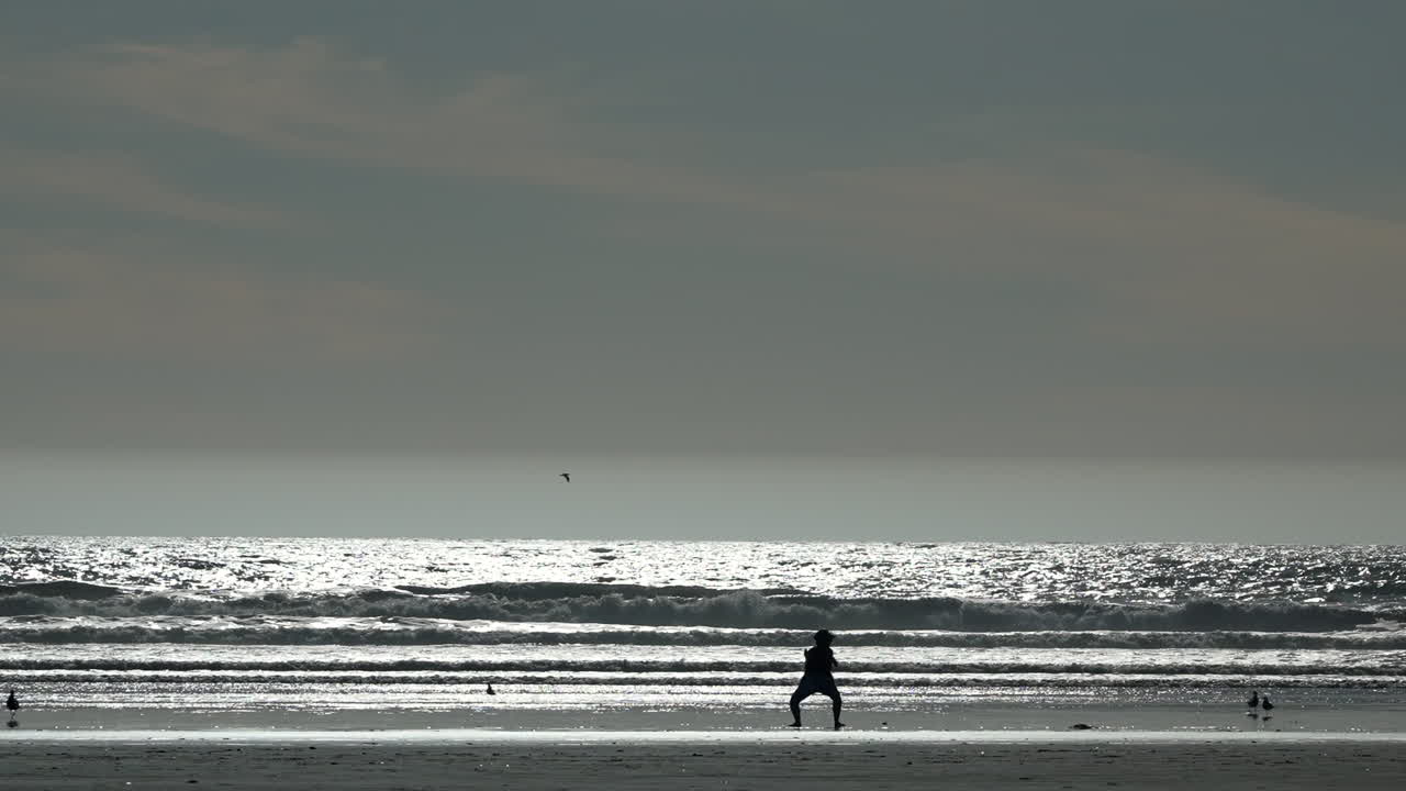 Silhouette di una persona che fa stretching ed esercizio sulla spiaggia all'alba o al tramonto