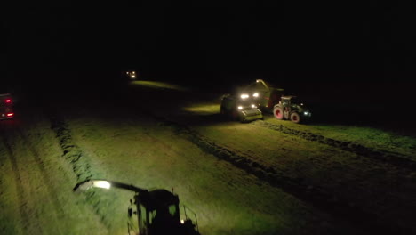 aerial views over farming vehicles working at night by spotlight