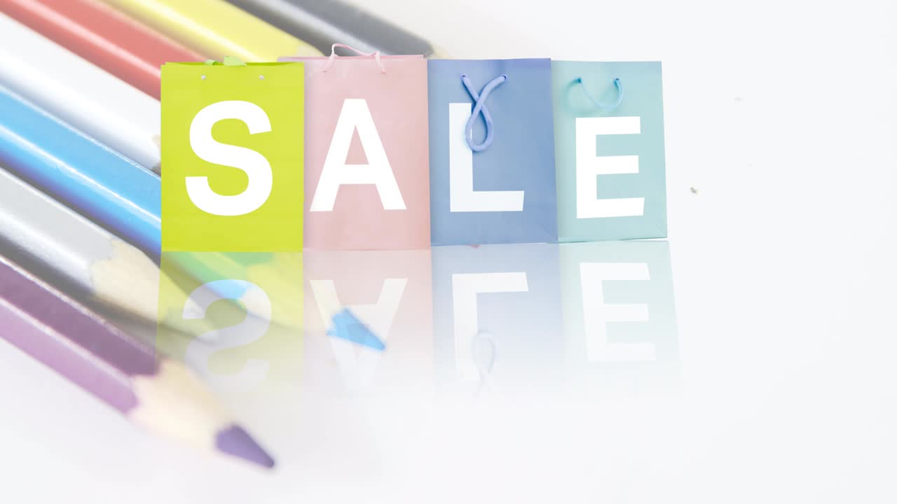 다채로운 쇼핑 가방과  ⁇ 색 배경에 있는 컬러 연필에 판매 텍스트의 애니메이션