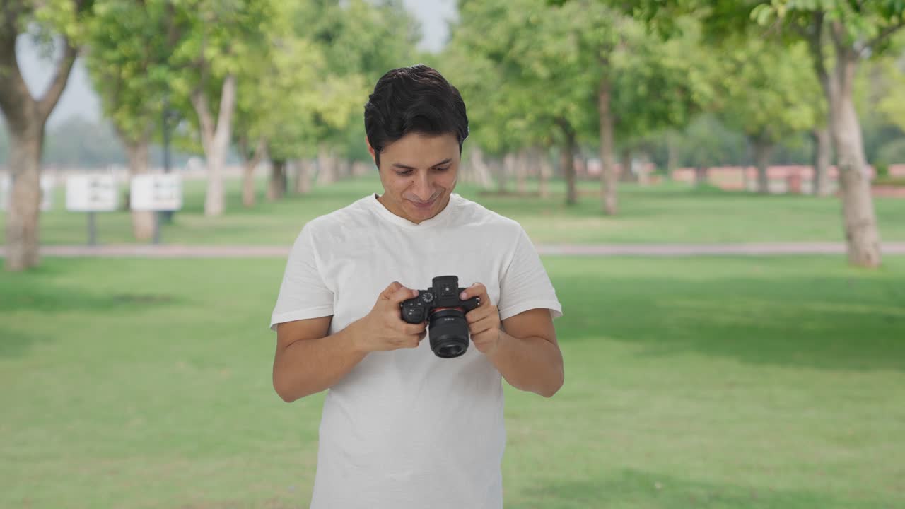 행복한 인도인 남자가 카메라를 사용하여 사진을 클릭합니다.