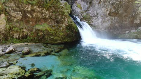 vista de dron en albania en los alpes todavía frente a una cascada rodeada por la montaña rocosa y verde en theth