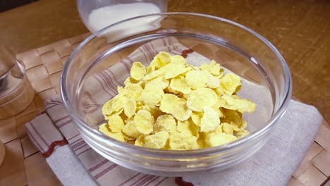 crispy yellow corn flakes into the bowl for the morning a delicious breakfast with milk. slow motion with rotation tracking shot.