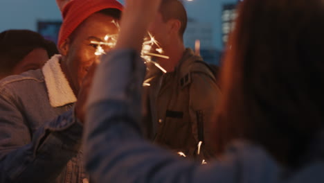 happy-friends-holding-sparklers-celebrating-new-years-eve-on-rooftop-at-sunset-having-fun-enjoying-holiday-party-celebration