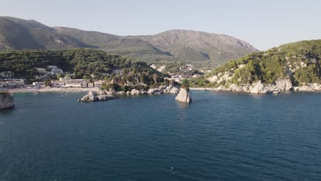 Aerial-view-of-small-rocky-islands,-traditional-architecture-and-coast-of-the-fishing-village-Parga-in-Greece