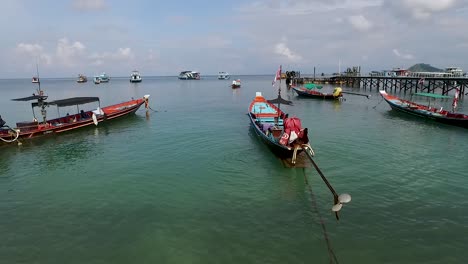 Empty-longtail-boats-in-shallow-water-pan-left-and-cloudy-sky-background