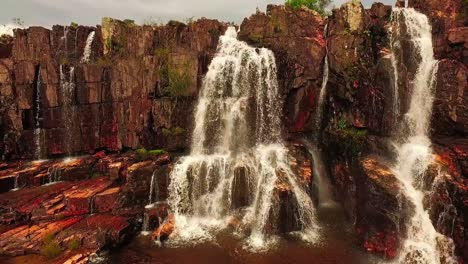 disparo de drones volando hacia y sobre una pequeña cascada a lo largo de un acantilado rocoso