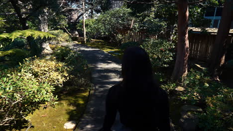 a 4k slow-motion, stabilized video following a beautiful young arabic female model exploring a lush japanese tea garden walking along a garden path, peninsula, california