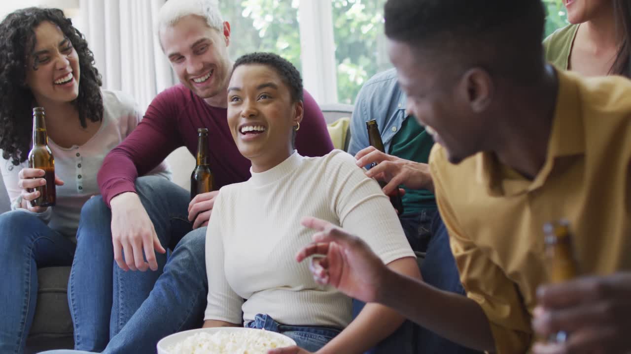grupo diverso de amigos felices masculinos y femeninos viendo deportes bebiendo cerveza, animando en la sala de estar
