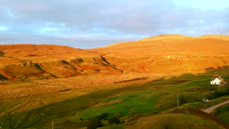 Panning-shot-of-the-beautiful-Fairy-Glen-hills-with-a-single-house-in-the-valley