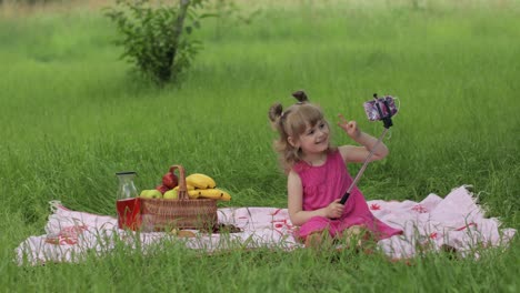 Weekend-at-picnic.-Girl-on-grass-meadow-makes-selfie-on-mobile-phone-with-selfie-stick.-Video-call