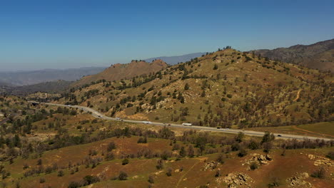 steady traffic flows along a highway through the tehachapi mountains on a bright but hazy day - aerial view