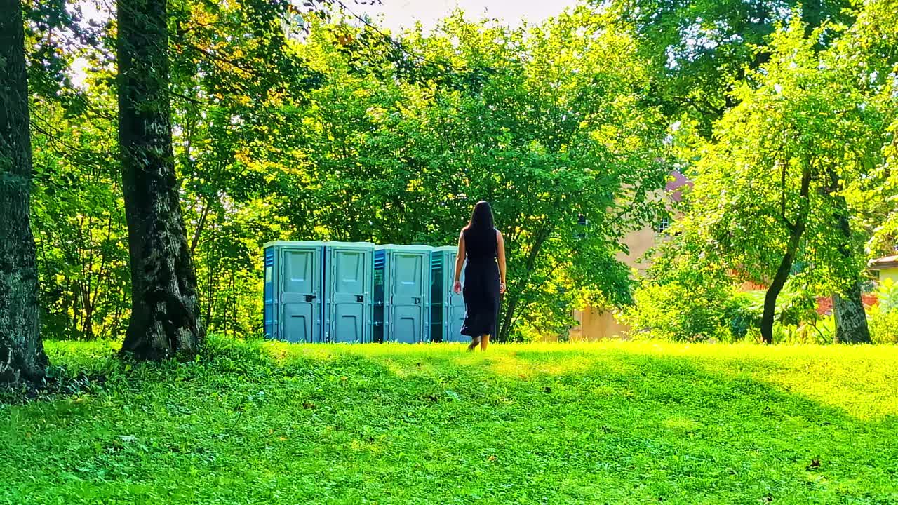 Woman walking towards portable toilets in a park