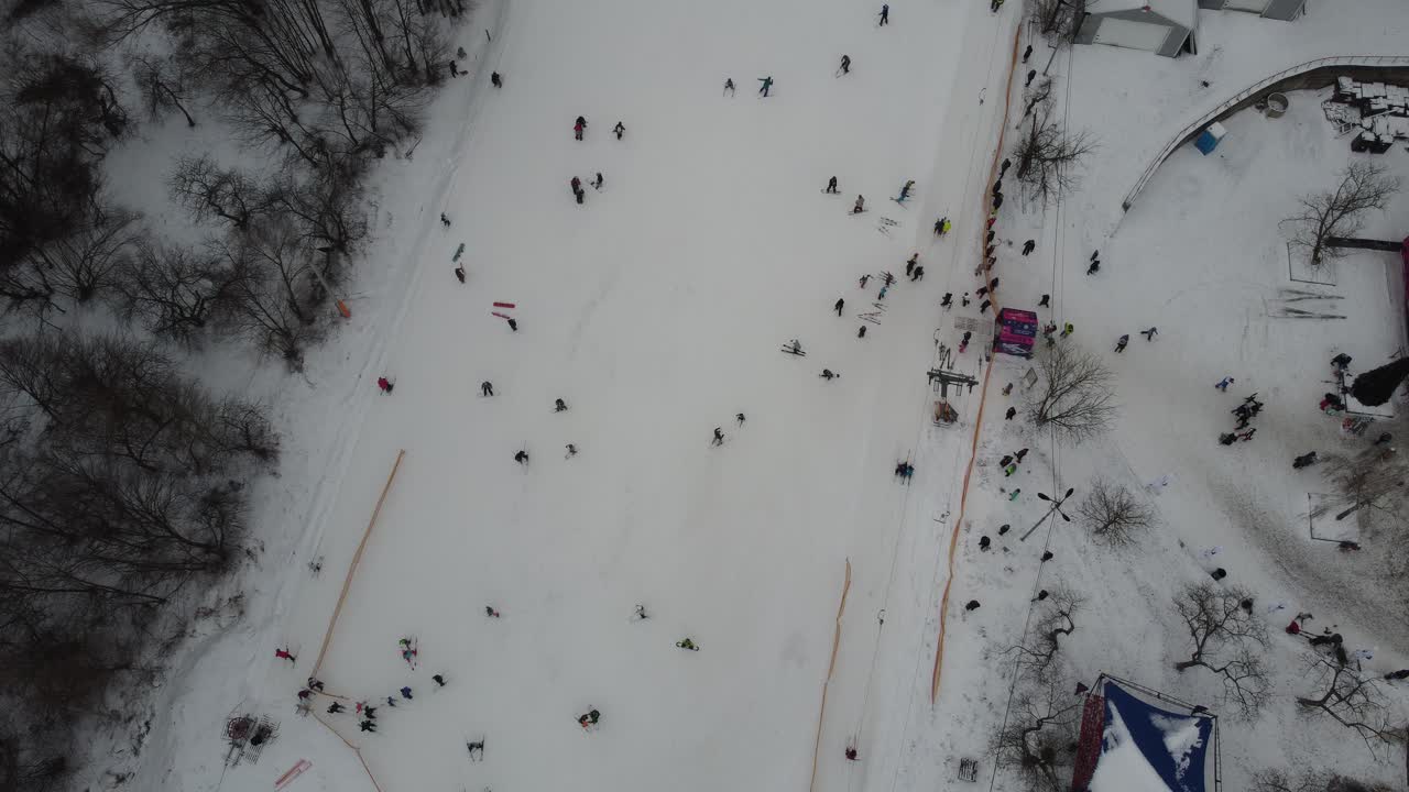 esquiadores y practicantes de snowboard esquiando en pistas de nieve con remonte los fines de semana. drone volando sobre una pendiente nevada con esquiadores y practicantes de snowboard en una estación de esquí en un día helado de invierno: vista de drones