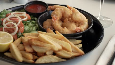 enjoying a mouthwatering seafood feast with crispy shrimp, fresh salad, and golden fries at a seaside restaurant