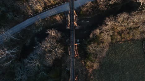 aerial top down shot of the pope lick railroad trestle and the surrounding woods and stream during sunset in louisville kentucky