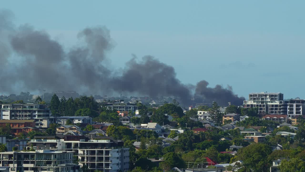 A commercial building in Kedron engulfed by a structure fire, with a thick column of smoke billowing into the air, visible from Bowen Hills.