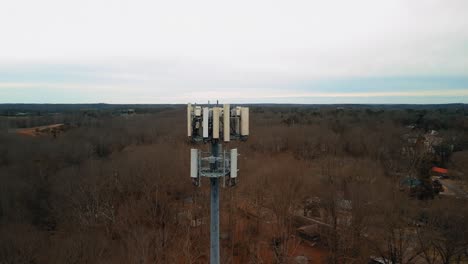 aerial reverse shot of cell phone tower surrounded by forest