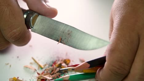 Footage-of-hands-slowly-sharpening-a-pencil-and-some-coloured-pencils-with-a-sharp-knife