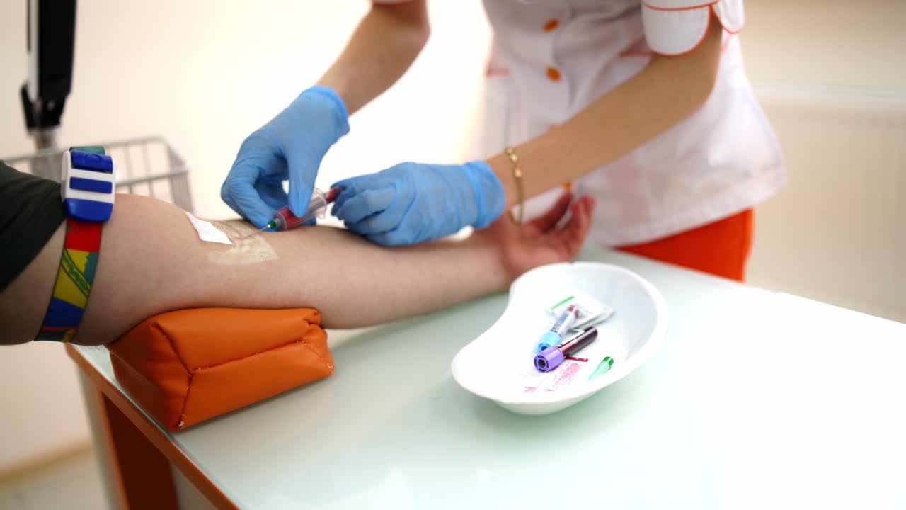 Nurse collecting blood from patient. Close up of doctor injecting patient with syringe to collect blood sample
