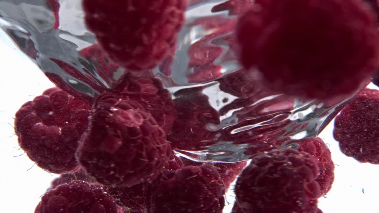Clear raspberry beverage funnel inside glassware closeup. Cold cocktail spinning