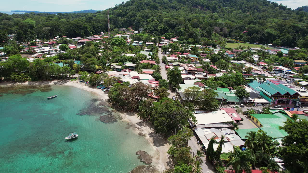 An aerial over downtown Puerto Viejo, a tropical Central American travel destination in Costa Rica, with coral reefs and fishing boats docked in the bay by the lush and scenic beach.
