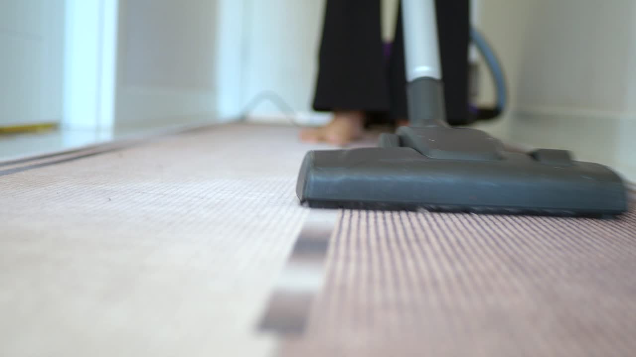 Person vacuuming a hallway carpet