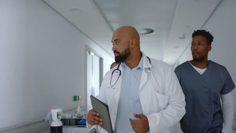 diverse male doctors talking in hospital corridor, slow motion