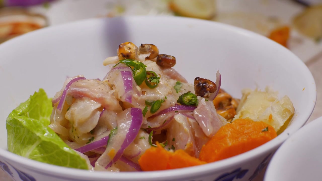 Video in slow motion del servizio di Ceviche peruviano in una ciotola, con patate dolci, su lattuga e guarnito con mais peruviano tostato