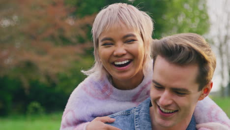loving couple outdoors in countryside with man giving woman piggyback