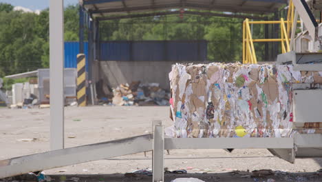 truck drives by paper bale at recycling facility, wide static shot