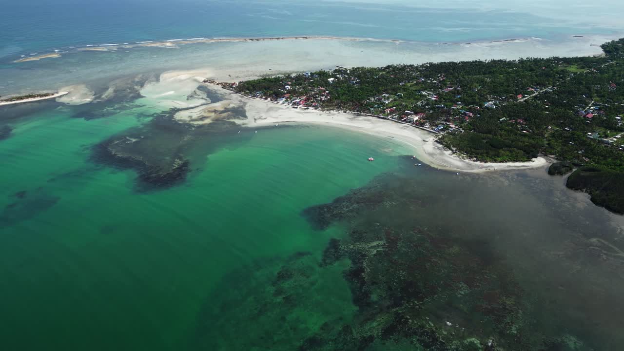 Ângulo aéreo diagonal mostrando a costa de uma ilha alinhada com palmeiras, areia branca e água cristalina em Tondol