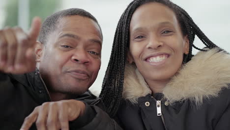 Afro-American-young-girl-with-braids-and-Afro-American-middle-aged-man-in-jacket-with-fur-hood-looking-at-camera