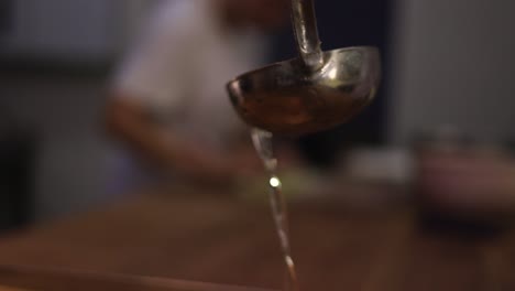 cuchara de cocción vertiendo jarabe sobre el postre con el pastelero en segundo plano.