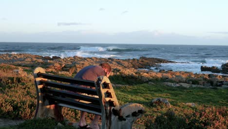 Anguished-man-on-bench-next-to-ocean-being-very-emotional