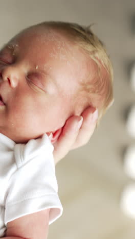 beautiful blond baby sleeping on mom's hand. newborn sleeping tight waved by his mother. close up. vertical video
