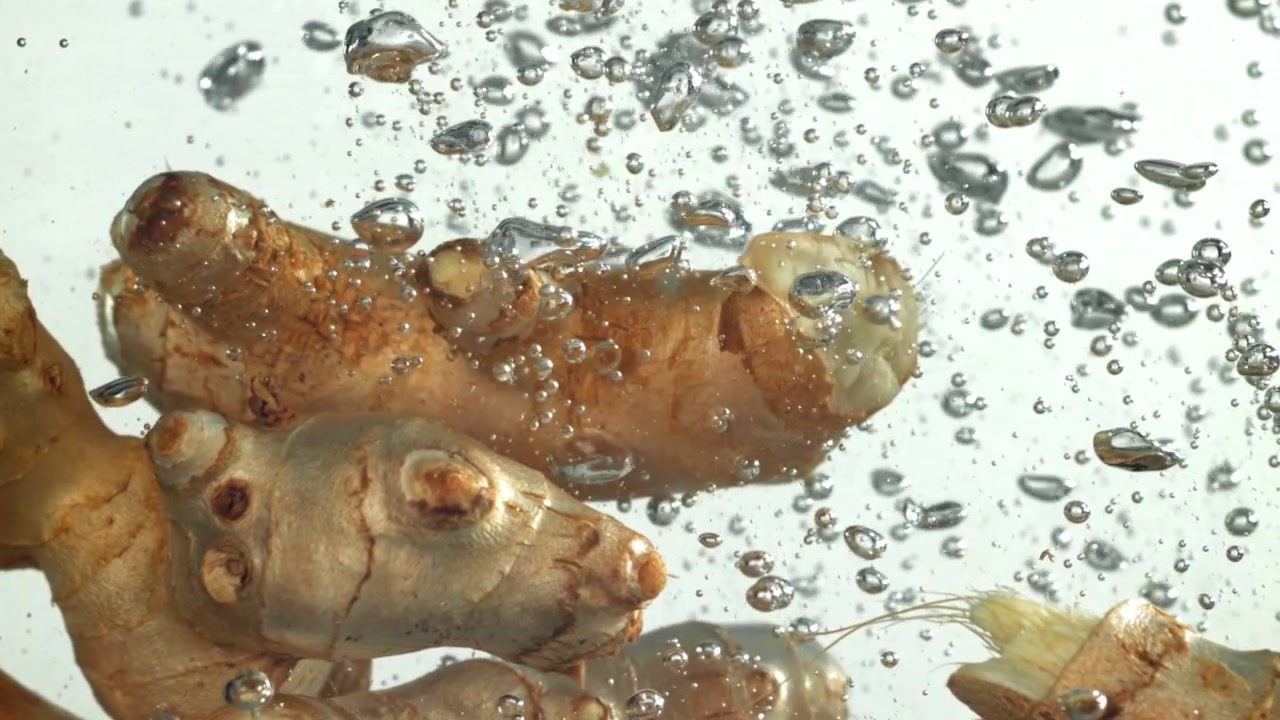 Primo piano di radice di zenzero sommersa nell'acqua con bolle che salgono