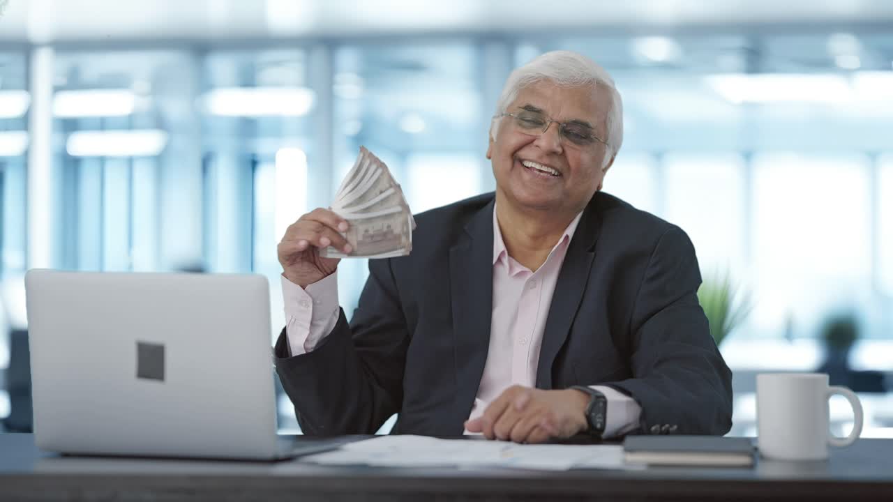 indiano feliz empresário sênior usando dinheiro como fã