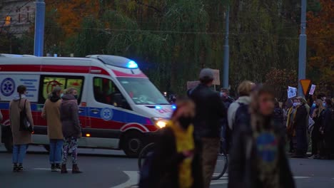 people protesting against abortion ban on the street of szczecin in poland. ambulance passes by on the road - wide shot, slow motion