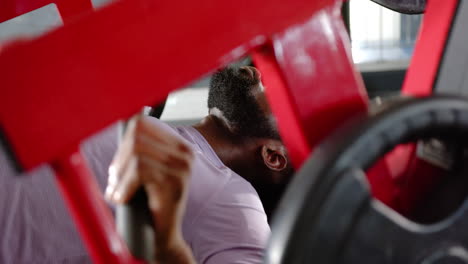 lifting weights on bench press, african american man focusing on strength training in gym
