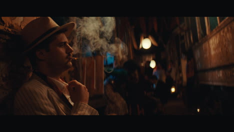 a man in hat smokes a cigarette in the circus camp