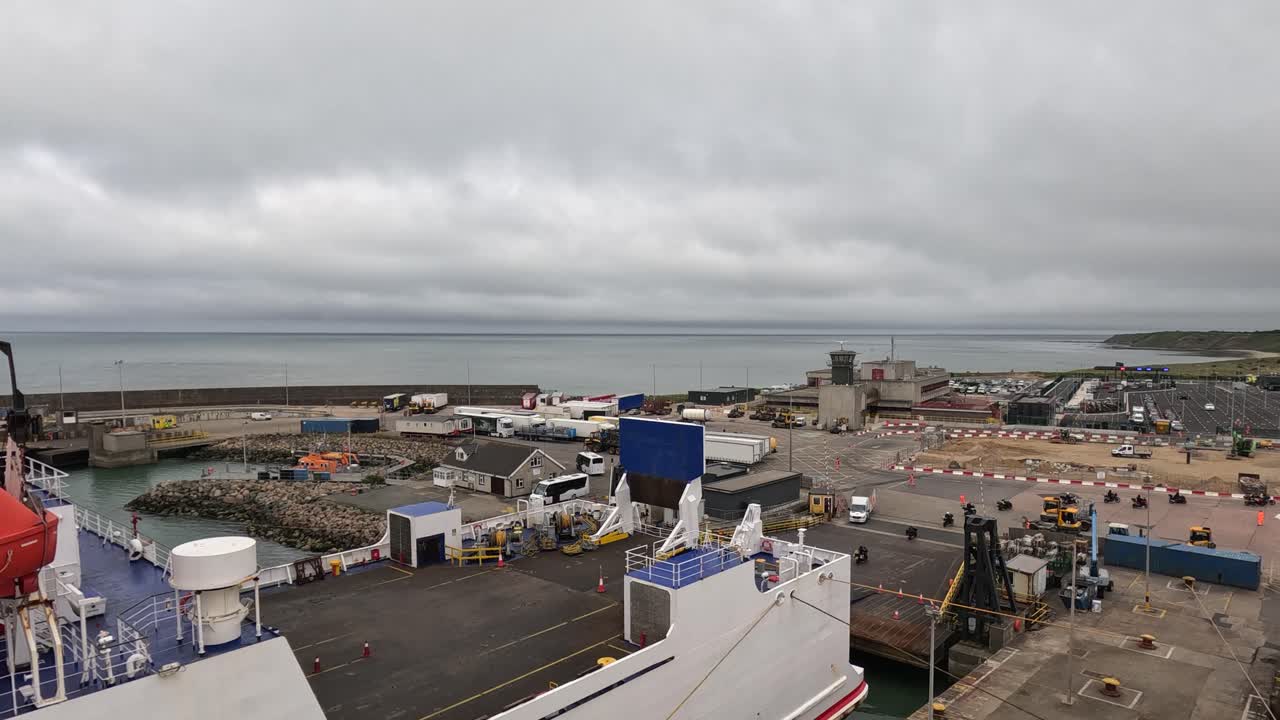Motorcyclists disembark from large transport ferry under overcast sky