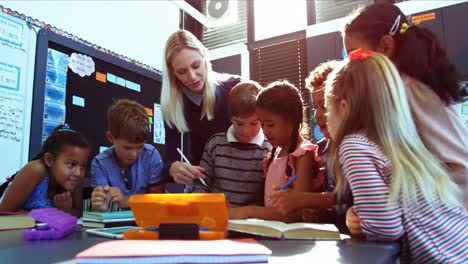 Teacher-helping-schoolkids-with-their-homework-in-classroom